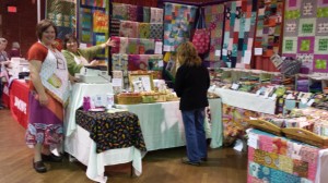 Rhonda, wearing a green top and a big smile is in the Sew Fresh Fabrics booth at the Quilters Gathering Quilt Show in Manchester, NH in 2013. Such a vivacious lady! Sew Fresh Fabrics had a booth at the 2013 Maine Quilt Show in Augusta.